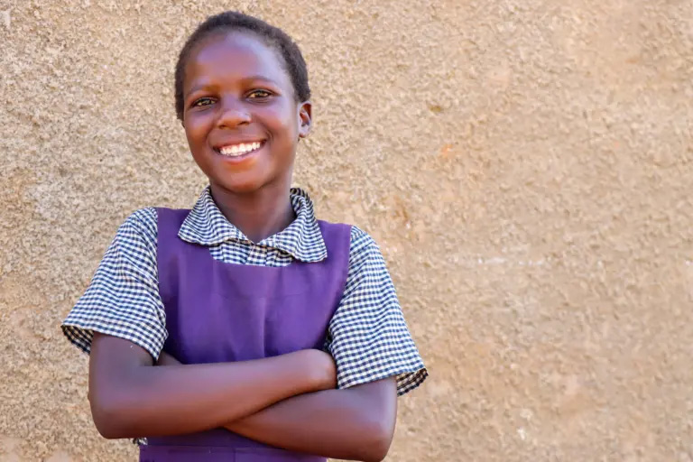 A girl in her school uniform smiling for the camera. Photo provided by World Vision.